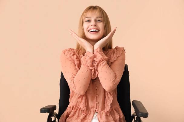 Ευτυχισμένη νεαρή γυναίκα σε αναπηρικό καροτσάκι σε μπεζ φόντο - Φωτογραφία, εικόνα
