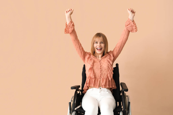 Szczęśliwa młoda kobieta na wózku inwalidzkim na beżowym tle - Zdjęcie, obraz