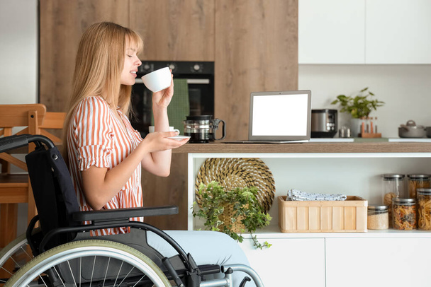 Mladá žena na invalidním vozíku pít kávu doma - Fotografie, Obrázek