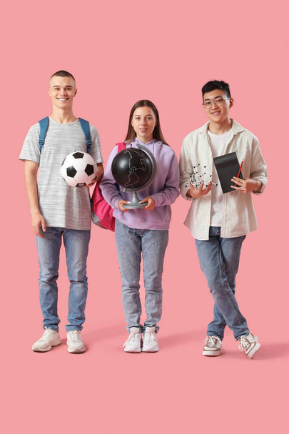 Estudiantes felices con balón de fútbol, globo y modelo molecular sobre fondo rosa - Foto, Imagen