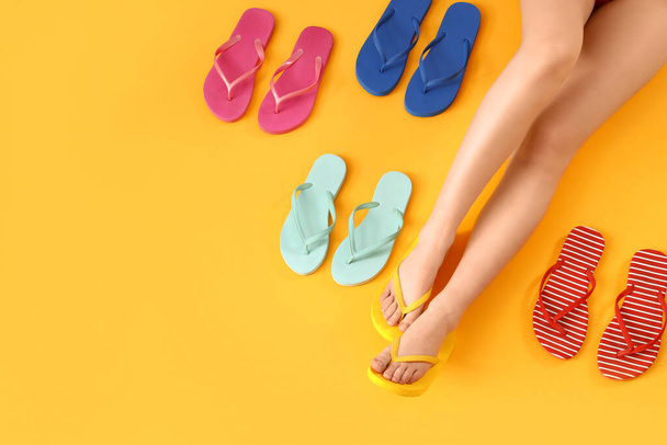 Female legs with different colorful flip flops on yellow background - Photo, Image