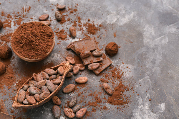 Ciotola con cacao in polvere, caramelle, fagioli e cioccolato su sfondo nero - Foto, immagini