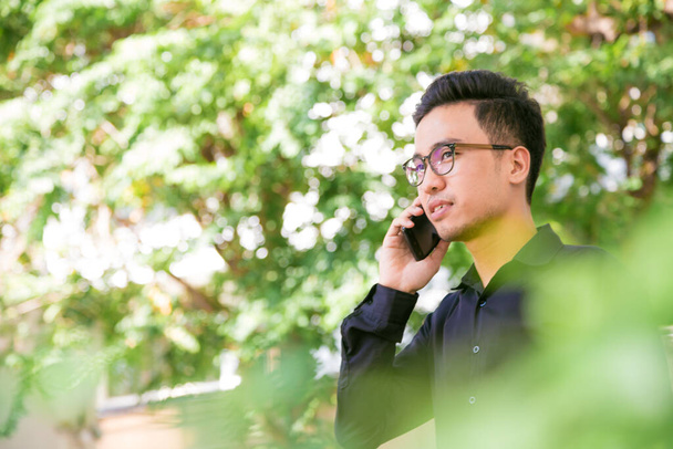Park açık havada güneşli bir günde telefonda konuşurken telefon ile Asya adam - Fotoğraf, Görsel