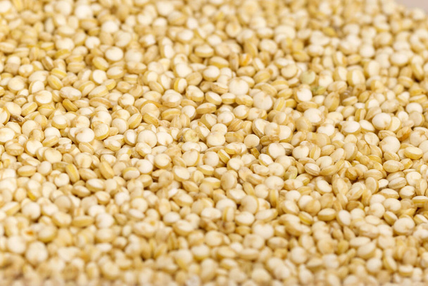 Nahaufnahme Makroaufnahme der trockenen leichten Quinoa-Körner, die auf einer ebenen Oberfläche liegen. - Foto, Bild