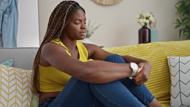 Donna afroamericana stressata seduta sul divano a casa - Filmati, video