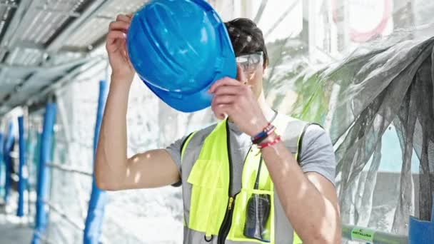 Jonge Spaanse man architect draagt een helm met een serieus gezicht op de bouwplaats - Video