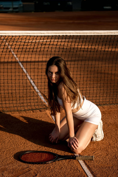 портрет теннисистки женщины в белой форме с ракеткой на корте, спортсменки стоят у теннисной сетки  - Фото, изображение