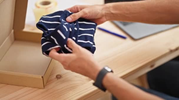 Joven hombre hispano comercio electrónico negocios embalaje camiseta en cardbord box en la oficina - Imágenes, Vídeo