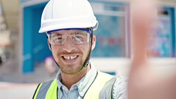 Young caucasian man architect smiling confident having video call at construction place - Footage, Video