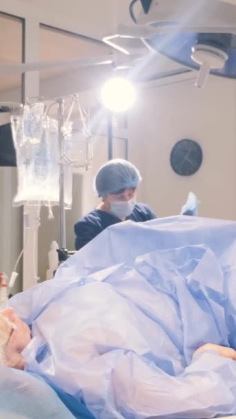 Chirurgen operieren die Beine einer älteren Frau mit Krampfadern. Der Arbeitsprozess der Chirurgen. Vertikales Video - Filmmaterial, Video