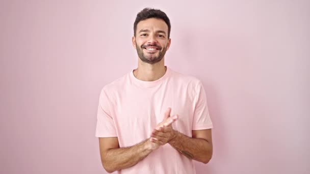 Joven hombre hispano sonriendo confiado aplaudiendo sobre aislado fondo rosa - Metraje, vídeo