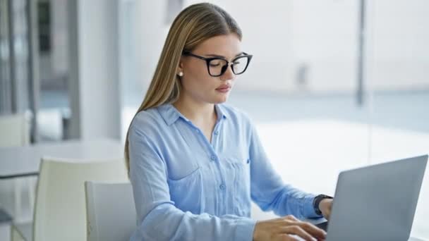 Fiatal szőke nő üzleti dolgozó laptoppal dolgozik az irodában - Felvétel, videó