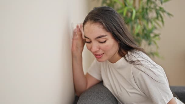 Νεαρή όμορφη ισπανίδα γυναίκα ακούει μέσα από τον τοίχο με γυαλί στο υπνοδωμάτιο - Πλάνα, βίντεο