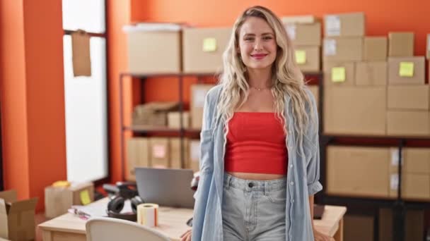 Joven mujer rubia comercio electrónico trabajador de negocios de pie con los brazos cruzados gesto en la oficina - Imágenes, Vídeo