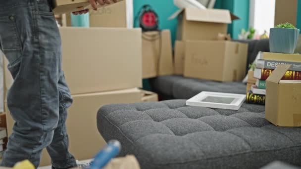 Jovem hispânico homem colocando pacote no sofá sofrendo de dor nas costas em nova casa - Filmagem, Vídeo