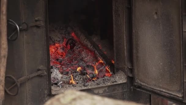 Open vintage houtkachel. Het vuur brandt in de oude oven, de vuurkist, het aanmaakvuur, het brandhout in de oven. Warme warmte. Close-up van de oven met open deur, vooraanzicht - Video