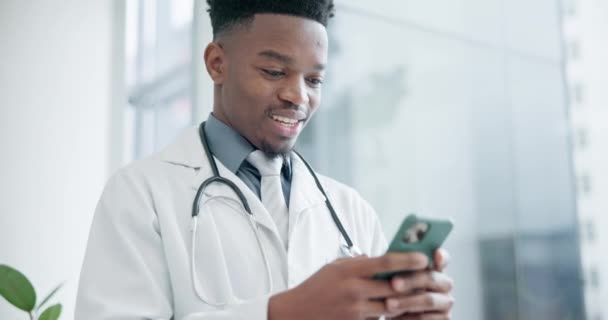 Muž, smartphone a lékař psaní v nemocnici pro on-line kontakt, čtení oznámení o zdravotní péči nebo telehealth info. Šťastný zdravotnický pracovník, africký chirurg a výzkum mobilní aplikace pro digitální síť. - Záběry, video