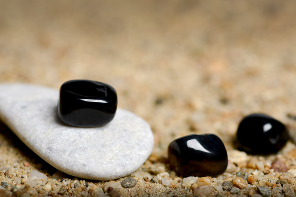 graue und schwarze Steine im Sandhintergrund - Foto, Bild