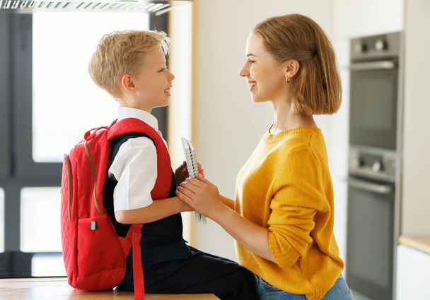 Перший день у школі. Мати дає блокноти щасливому синові під час підготовки до навчання вдома - Фото, зображення