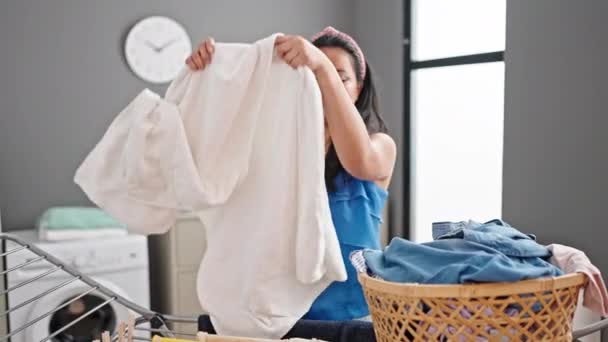 Młoda Chinka pachnąca czystym ręcznikiem stojąca przy sznurze ubrań uśmiechnięta do pralni - Materiał filmowy, wideo