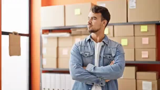 Young hispanic man ecommerce business worker standing with arms crossed gesture at office - Imágenes, Vídeo