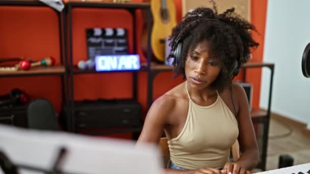 Músico afroamericano tocando el piano quitándose los auriculares cansado en el estudio de música - Metraje, vídeo