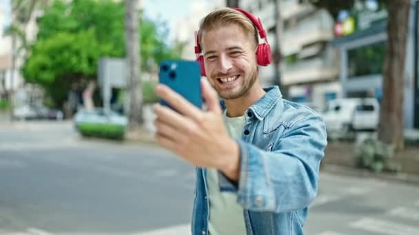 jonge Kaukasische man glimlachen zelfverzekerd met video bellen op straat - Video