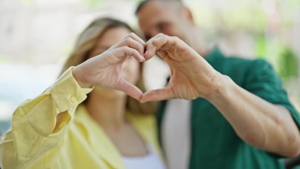 Muž a žena pár dělá srdeční gesto s rukama líbání na ulici - Záběry, video