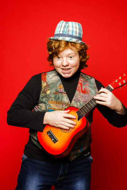 Рыжий смешной подросток, играющий на маленькой гитаре
 - Фото, изображение
