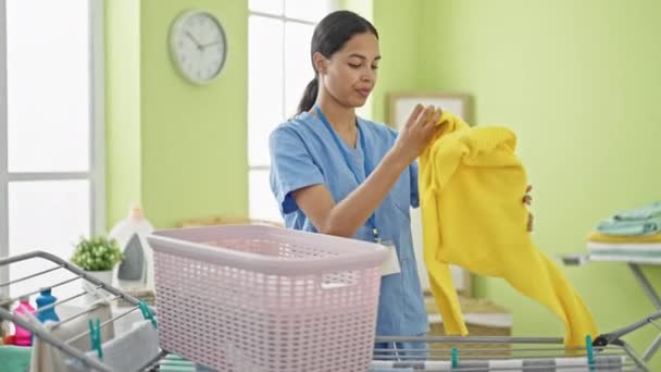mulher afro-americana profissional limpador pendurado roupas no varal na lavanderia - Filmagem, Vídeo