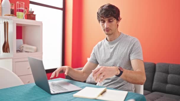 Fiatal spanyol férfi használ laptop írás notebook hangsúlyozta ebédlőben - Felvétel, videó