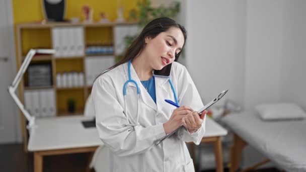 Młoda, piękna latynoska lekarka pisząca na dokumencie mówiącym na smartfonie w klinice - Materiał filmowy, wideo
