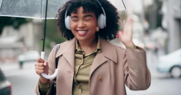 Music, headphones and woman dance in city, street or walking with radio, song or hear techno audio with tech. Happy, listening and person streaming hip hop, track or podcast in the rain with umbrella. - Footage, Video