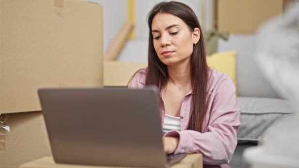 Mujer hispana hermosa joven usando el ordenador portátil sentado en el piso pensando en casa nueva - Imágenes, Vídeo