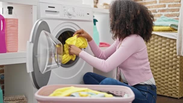 Африканська американка миє одяг, роблячи великий палець жестом у пральні - Кадри, відео
