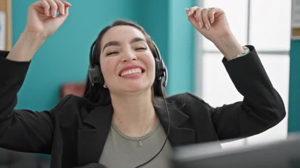 Νεαρή όμορφη ισπανόφωνη επιχειρηματίας χρησιμοποιώντας υπολογιστή και ακουστικά γιορτάζει στο γραφείο - Πλάνα, βίντεο