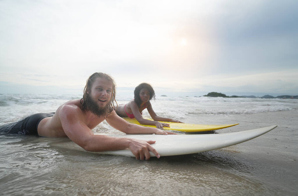 Счастливая пара серфинга вместе на пляже с доской для серфинга в Паттайе, Таиланд. - Фото, изображение