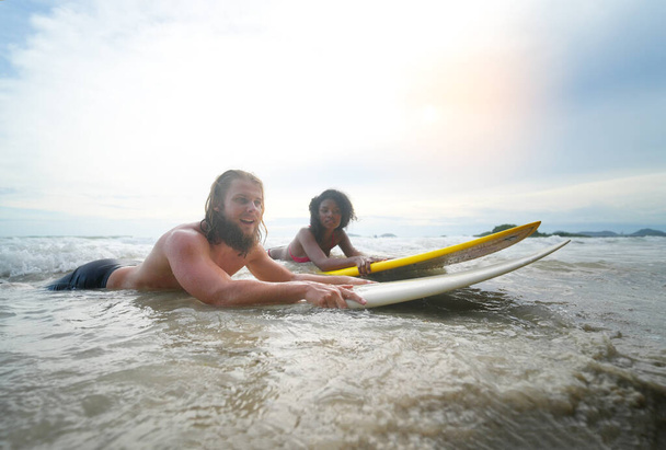 Счастливая пара серфинга вместе на пляже с доской для серфинга в Паттайе, Таиланд. - Фото, изображение