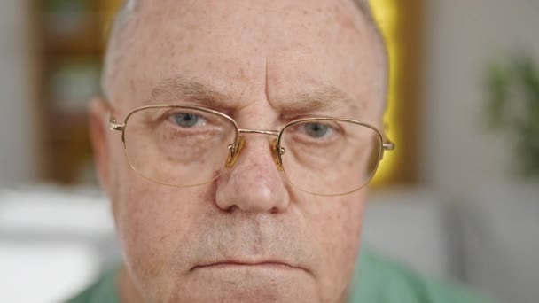 Mężczyzna w średnim wieku siwe włosy siedzi na kanapie z relaksującym wyrazem twarzy w domu - Materiał filmowy, wideo