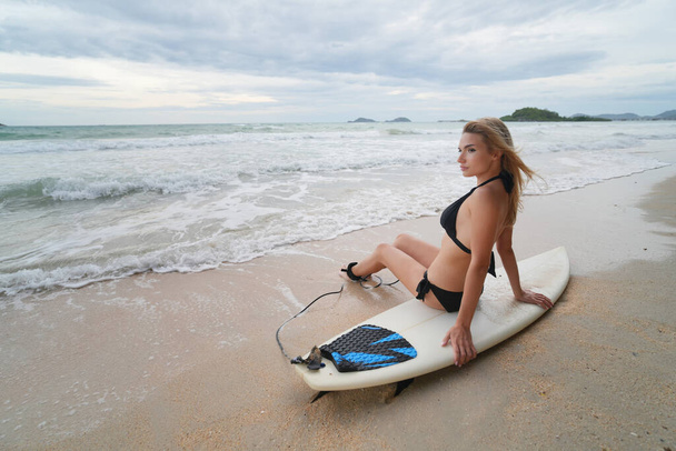 Szexi nő pózol szörfdeszkával a strandon - Fotó, kép