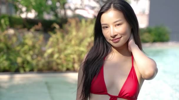 Close up portret pięknej Azjatki z czarnymi włosami w bikini uśmiecha się przy basenie. - Materiał filmowy, wideo