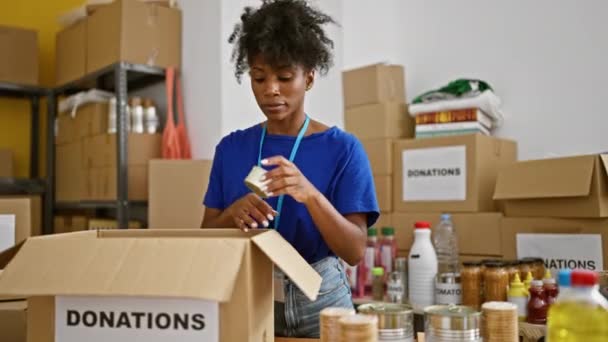 Africano americano mulher voluntária embalagem produtos no pacote no centro de caridade - Filmagem, Vídeo