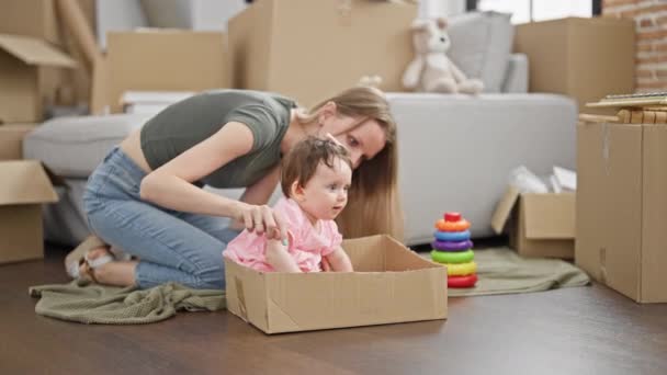 Madre e hija sentadas en el suelo jugando con aros de juguete en casa nueva - Metraje, vídeo