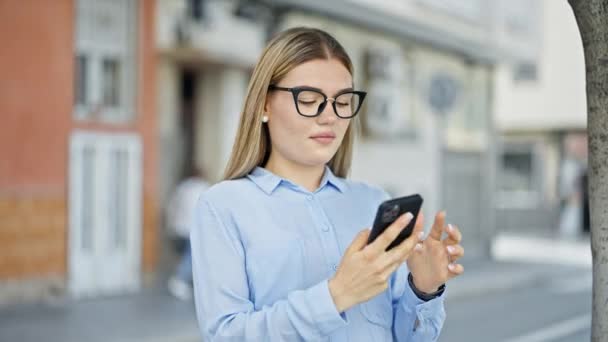 Young blonde woman business worker smiling confident talking on smartphone at street - Footage, Video