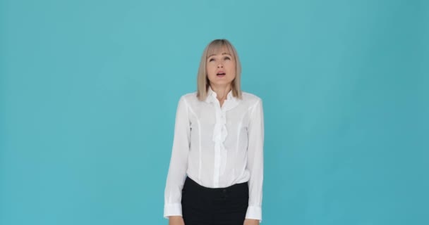 Caucasian woman is shown yawning and stretching on a serene blue background. Her tired expression and the yawn suggest her need for rest or relaxation. The blue backdrop adds a touch of tranquility. - Footage, Video