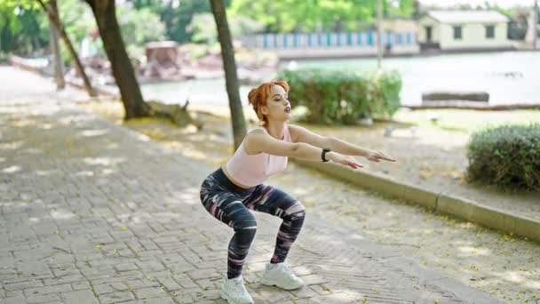 Jonge roodharige vrouw draagt sportkleding training benen oefening in het park - Video