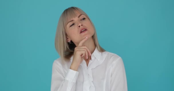 Puzzled businesswoman is depicted as she contemplates and makes a decision on blue background. Her thoughtful expression and hand gesture indicate her consideration and uncertainty about the choice. - Footage, Video