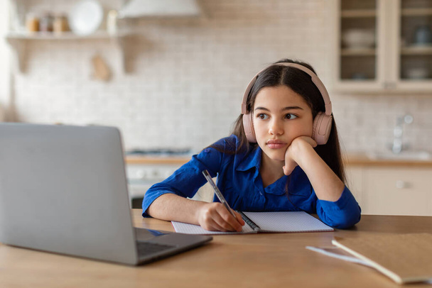 E-öğrenme sorunları. Sıkıcı ve Yorgun Öğrenci Kız Laptop İzleme Okulu Dersini İnternette Kullanıyor, Ev Mutfağında Oturan Masa Notları Alıyor. Üzgün Kız Bilgisayar 'da Ödev Yapıyor - Fotoğraf, Görsel
