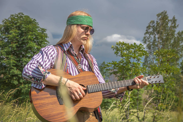 Hippie cara com uma guitarra em uma clareira floresta em um dia ensolarado - Foto, Imagem