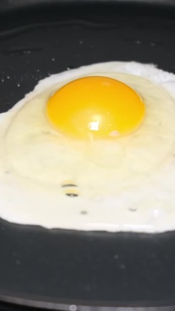 Kuřecí vejce v černé pánvi. Chutné, zdravé, proteinové jídlo. Svislé video - Záběry, video